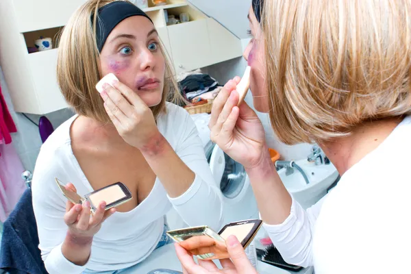Woman covering bruises with make up — Stock Photo, Image