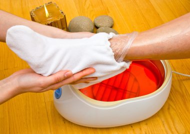 woman foot in paraffin bath at the spa clipart