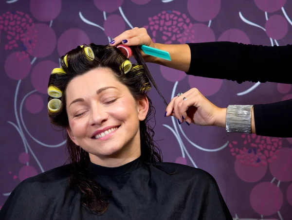 Cabeleireiro colocando rolos no cabelo da mulher — Fotografia de Stock