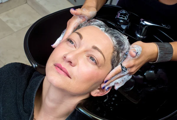 Mogen kvinna tvätta håret — Stockfoto