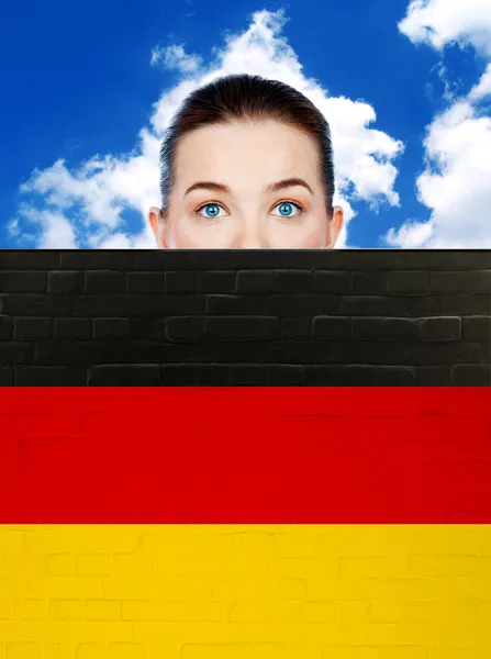 Woman face behind wall with german flag — Stock Photo, Image