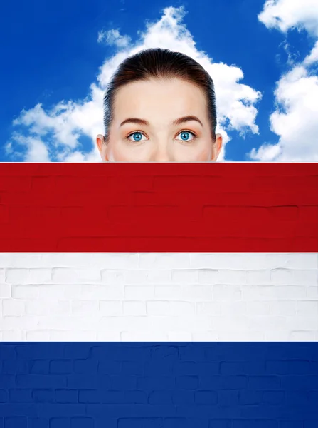 Vrouw gezicht achter de muur met Nederland vlag — Stockfoto