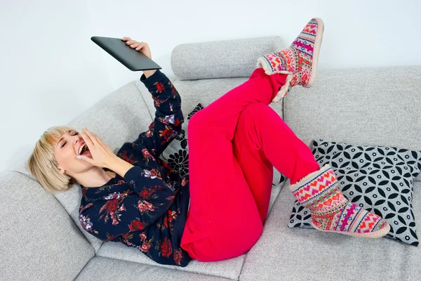 Attraktiv kvinna med tabletten i soffan på hoime — Stockfoto