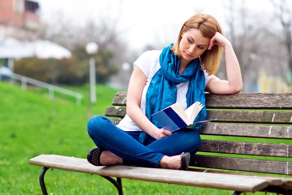 Attraktive Frau auf der Bank mit Buch — Stockfoto