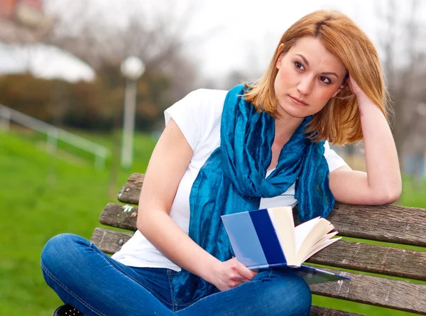 Attraktive Frau auf der Bank mit Buch — Stockfoto