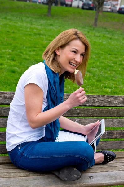 Привлекательная женщина с ноутбуком на скамейке в парке — стоковое фото