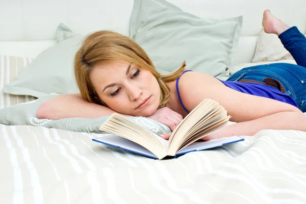 Женщина читает книгу в постели — стоковое фото