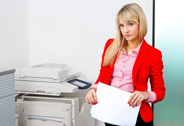プリンターの隣に立っている書類を持つ女性実業家 — ストック写真
