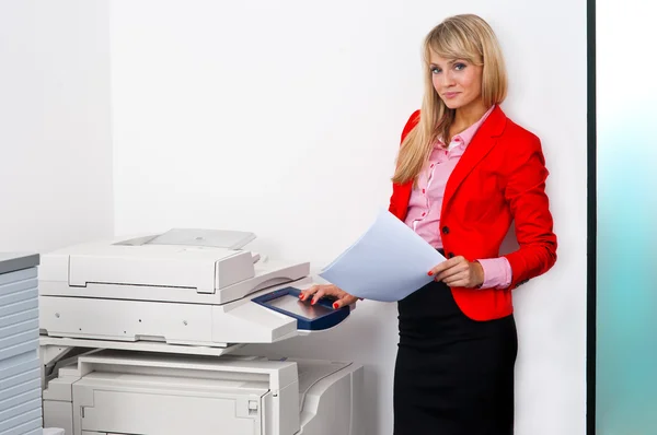 Mujer de negocios con documentos de pie junto a la impresora — Foto de Stock