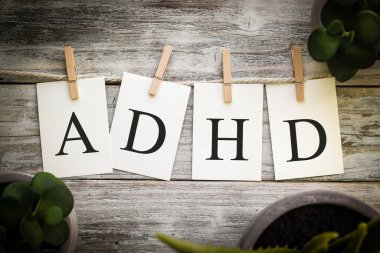 Eski ahşap arka planda ADHD kelimesini heceleyen bir dizi basılı kart..
