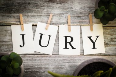Eski ahşap bir arka planda JURY sözcüğünü heceleyen bir dizi basılı kart.