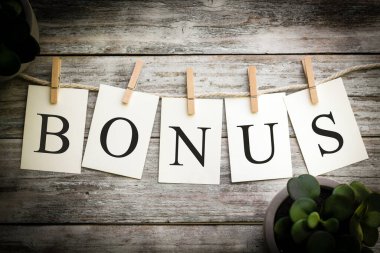 BONUS kelimesinin eski ahşap bir arka planda hecelendiği bir dizi basılı kart..
