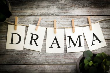 Eski ahşap bir arka planda DRAMA sözcüğünü heceleyen basılı kartlar..