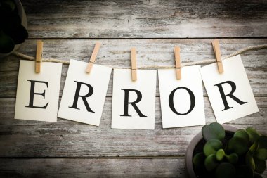 Eski ahşap bir arka planda ERROR sözcüğünü heceleyen bir dizi basılı kart.