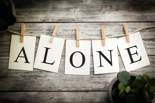 一张印有 Alone 字样的卡片 印在古老的木制背景上 — 图库照片