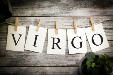Eski ahşap bir arka planda VIRGO sözcüğünü heceleyen basılı kartlar..