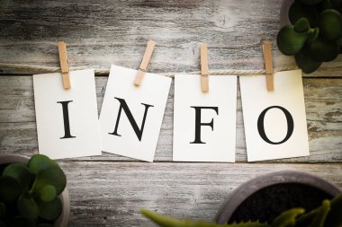 Eski ahşap bir arka planda INFO kelimesini heceleyen bir dizi basılı kart..