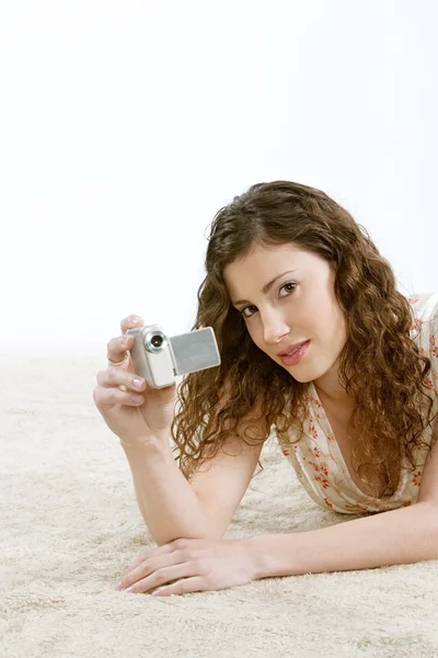 Woman looking at a digital video camera while laying down — Stock Photo, Image