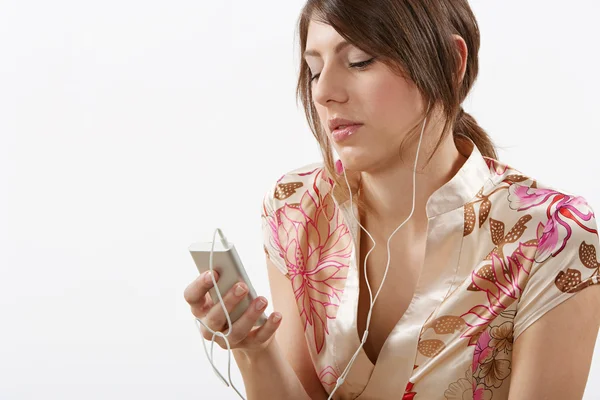 Mladá žena poslechu hudby pomocí její mp4 přehrávač a sluchátka — Stock fotografie