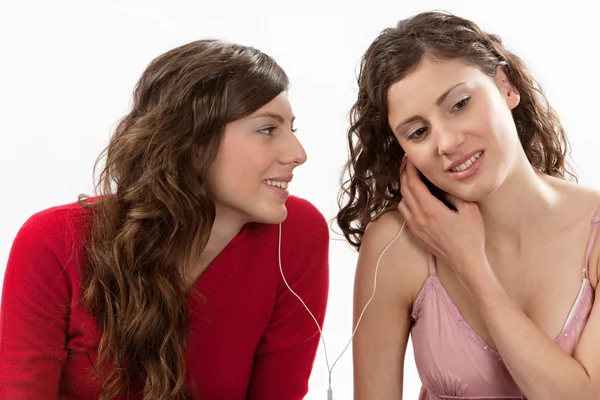 Duas jovens mulheres compartilhando seus fones de ouvido e ouvindo música — Fotografia de Stock