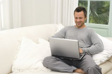 genç adam, evde bir dizüstü bilgisayar kullanarak