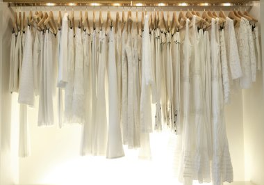 Yeni beyaz elbiseler moda mağaza ahşap askı üzerinde asılı bir satýr.