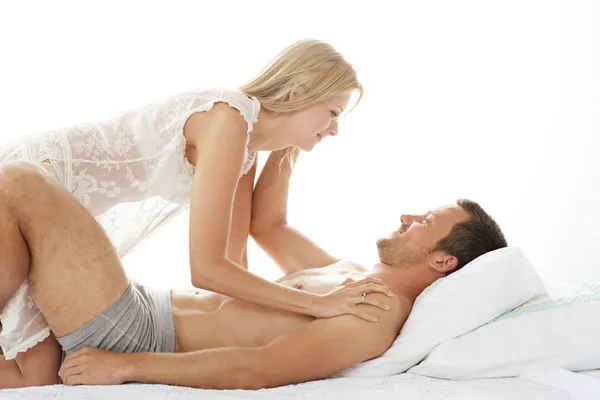 Kruipen over de mens in bed, speelse en lachende vrouw. — Stockfoto