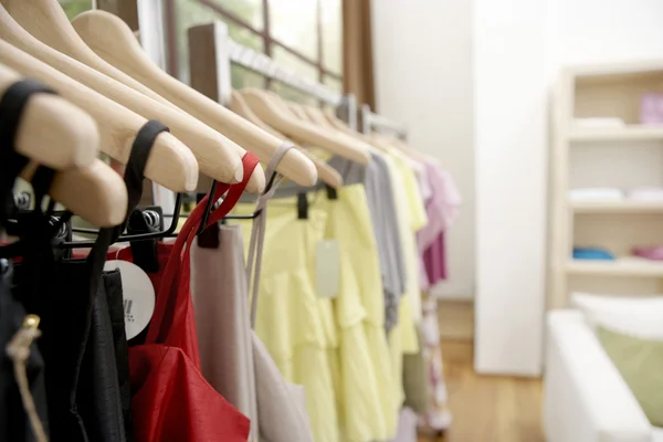 Clothes hanging on wooden hangers in a fashion store. — Stock Photo, Image