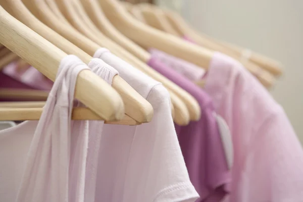 Деталь розовой одежды висит на деревянных вешалках в модном магазине . — стоковое фото