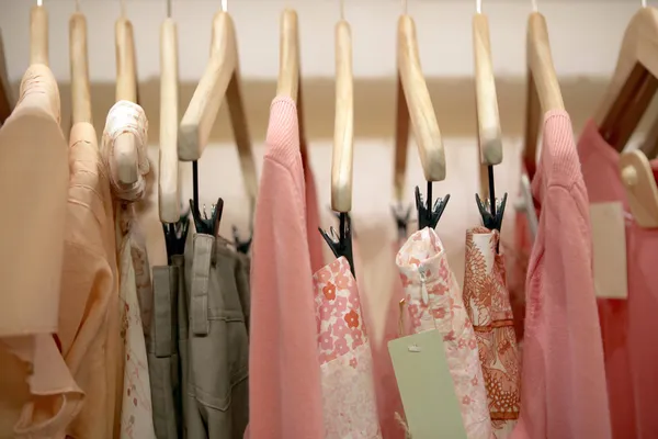 Hossz-szelvény nézet rózsaszín ruha lógott egy divat üzletben fa akasztók. — Stock Fotó