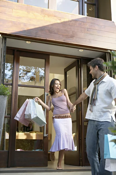 Casal saindo de uma loja elegante, segurando sacos de compras . — Fotografia de Stock