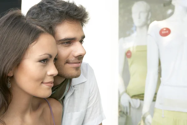 Acercamiento de una pareja joven al aire libre, mirando la ropa en la ventana de la tienda de moda . —  Fotos de Stock