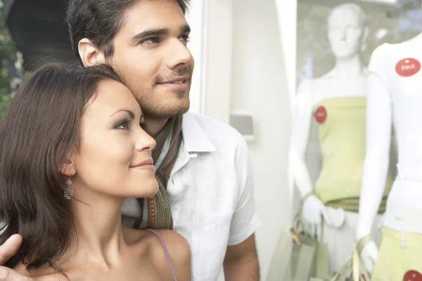 Acercamiento de una pareja joven al aire libre, mirando la ropa en la ventana de la tienda de moda . — Foto de Stock