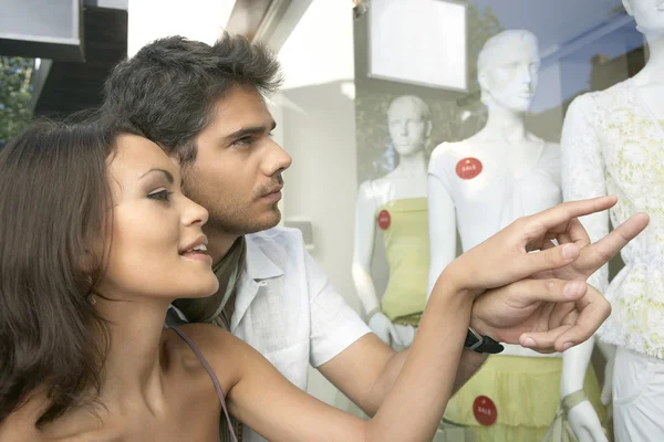 Acercamiento de una pareja joven al aire libre, mirando la ropa en la ventana de la tienda de moda . —  Fotos de Stock