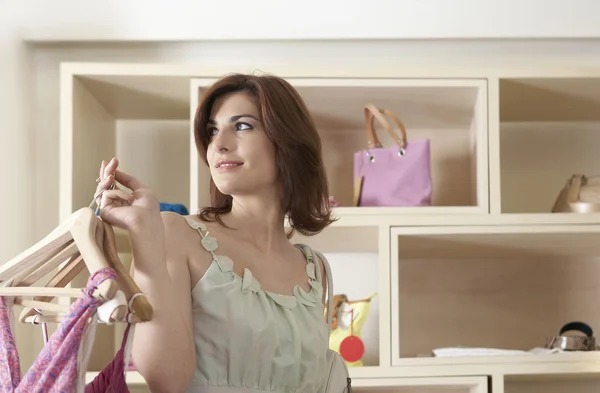 Sophisticated woman holding hangers with clothes in a store. — Stock Photo, Image