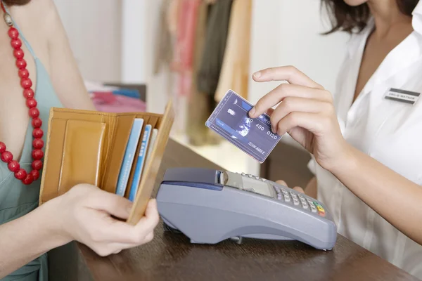 Close up detail of a store attendant holding a credit card near a card reader. — Stock Photo, Image