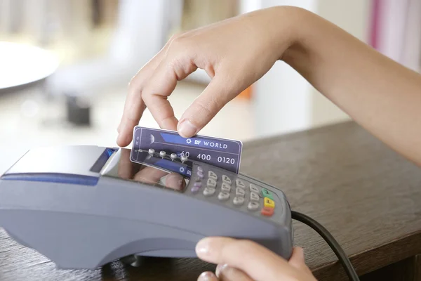Nahaufnahme der Hand einer Verkäuferin, die eine Kreditkarte in ein Kartenlesegerät fegt. — Stockfoto