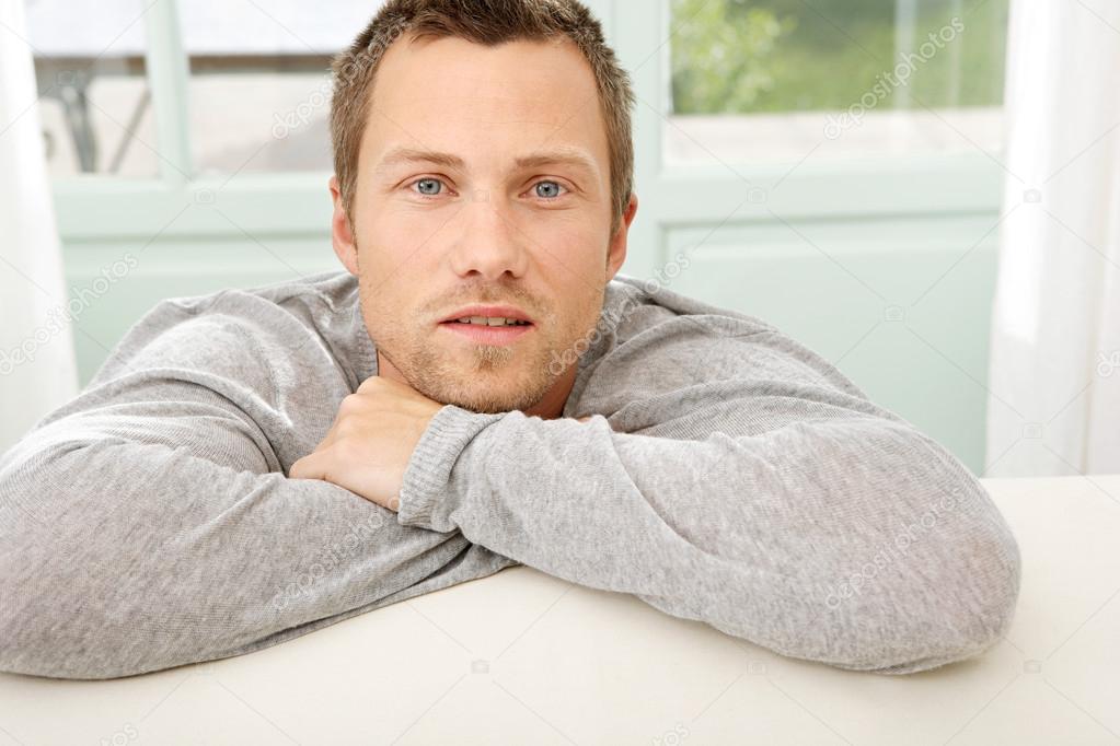 young professional man resting on a white sofa at home.