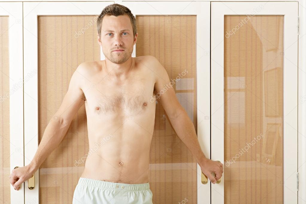 Attractive man in front of wardrobe doors in a bedroom in underwear