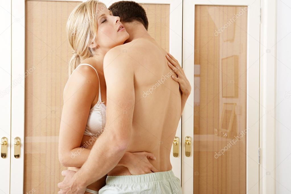 Sexy young couple passionately hugging in bedroom.