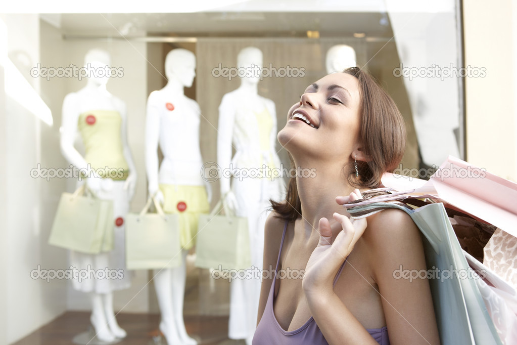 Portrait of a young woman feeling happy, holding shopping bags.