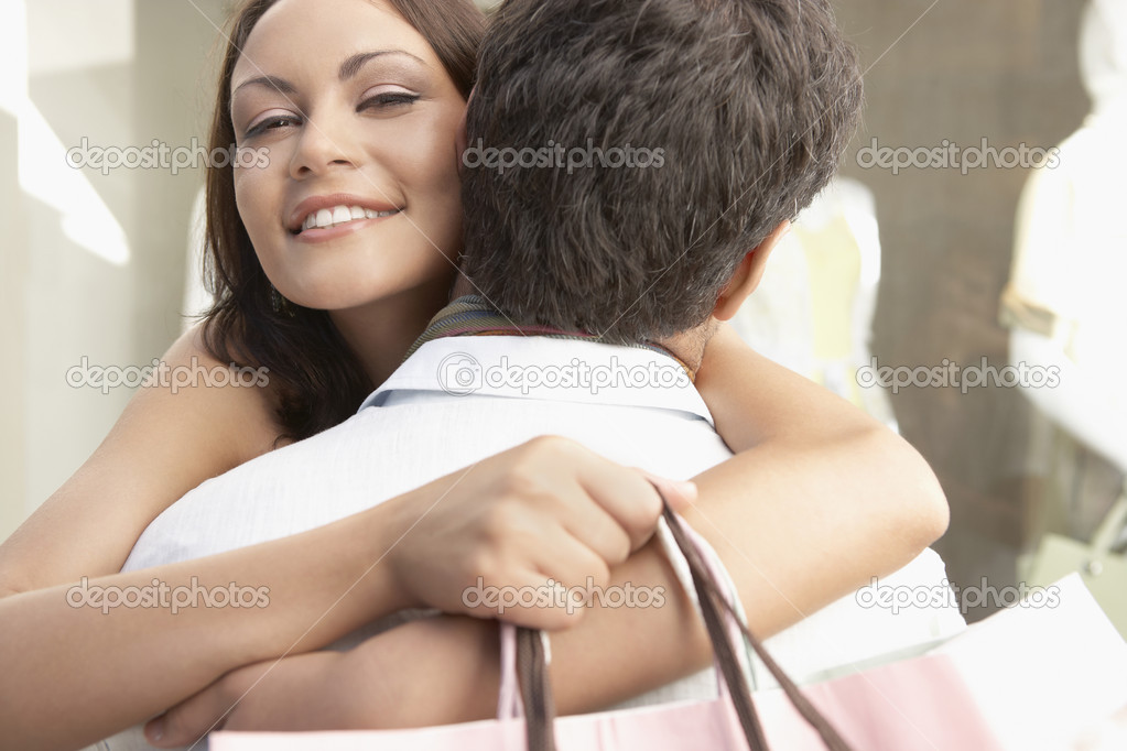Close up of a young couple hugging with shopping bags.