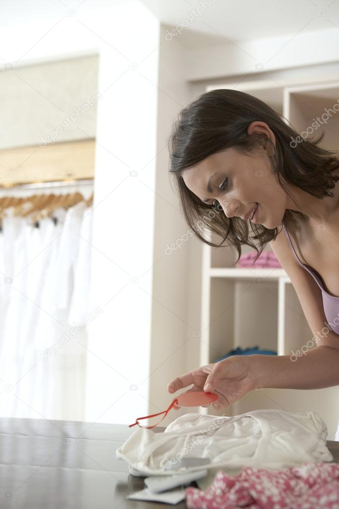 Attractive woman holding a blank price tag in a fashion store.
