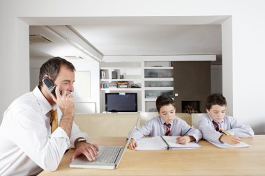 Father and two twin sons working together on a wooden table at home clipart