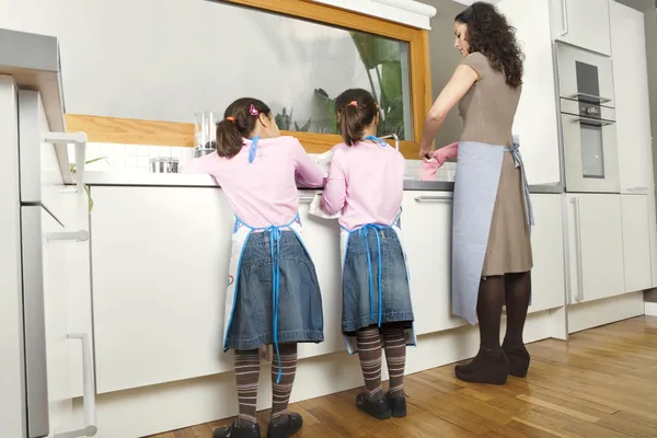 Mamma och två döttrar tvätta rätter i ett hem kök. — Stockfoto