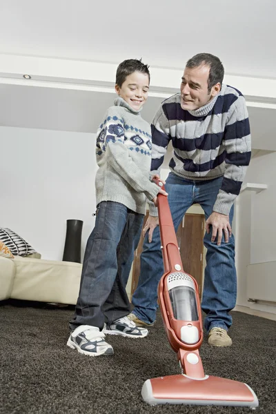 Pai e menino usando um limpador de vacum em casa . — Fotografia de Stock