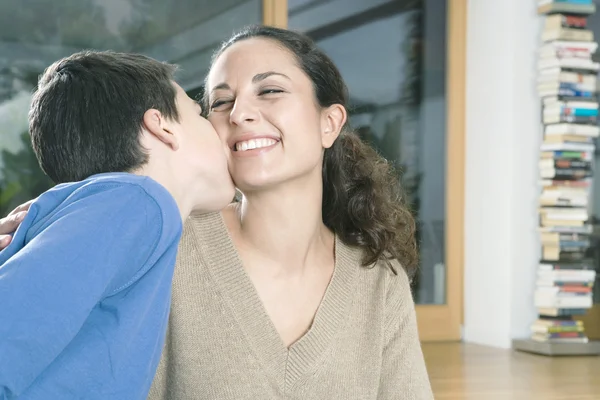 Jeune fils embrassant sa mère sur le ckeek . — Photo