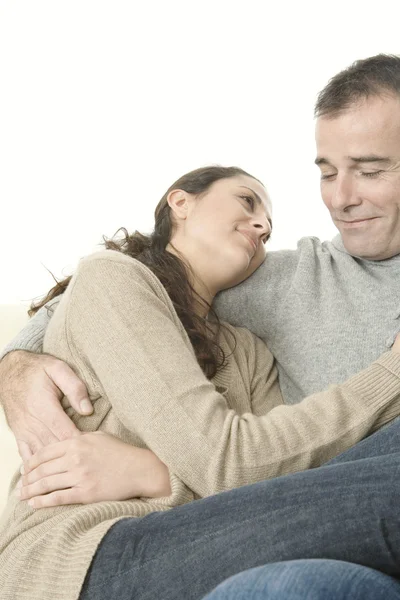 夫妇在沙发上轻松在家抱住对方微笑. — 图库照片