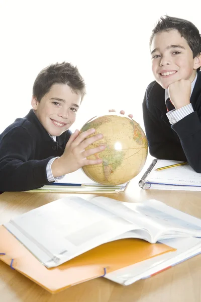 Dois irmãos gêmeos fazendo seus trabalhos de casa de geografia, usando um globo . — Fotografia de Stock