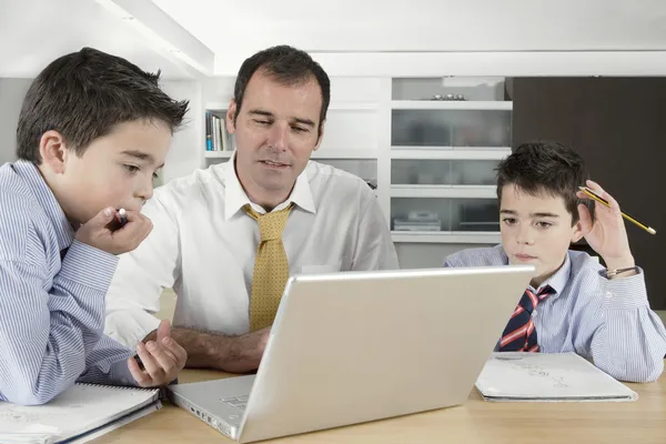 Père aidant ses fils jumeaux avec leurs devoirs à la maison . — Photo
